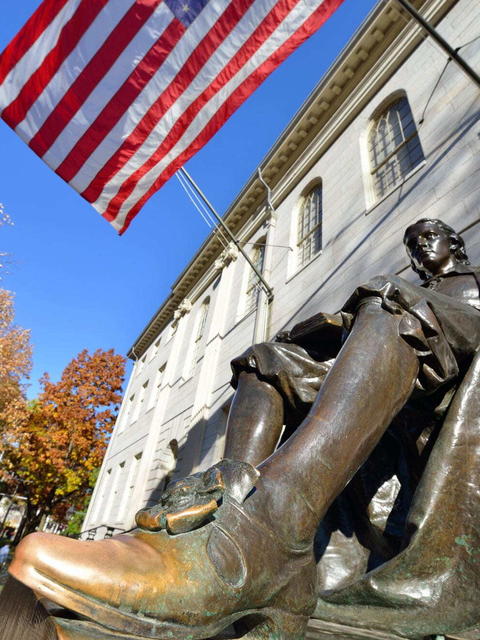 The John Harvard statue on a bright sunny day in Harvard Yard